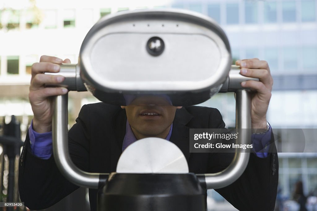 Businessman looking through a coin-operated binoculars