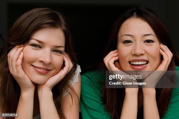 portrait of two young women smiling - leaning on elbows stock pictures, royalty-free photos & images