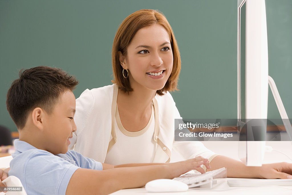 Female teacher with her student in front of a desktop PC