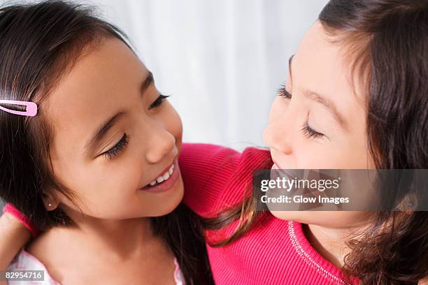 two schoolgirls looking at each other and smiling in a classroom - fossetta foto e immagini stock