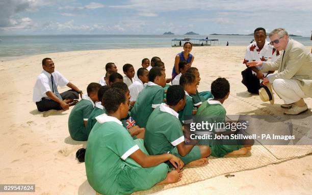 The Prince of Wales talks to a group of school children from the Malolo District School, having a lesson at the edge of the Pacific Ocean.