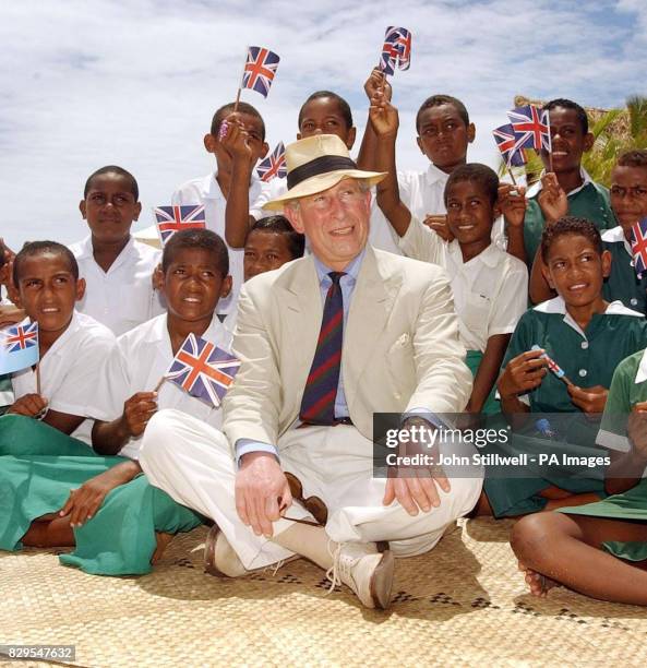 The Prince of Wales talks to a group of school children from the Malolo District School, having a lesson at the edge of the Pacific Ocean.