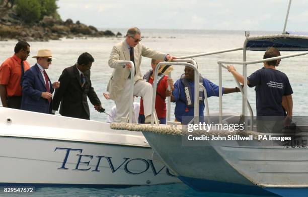 The Prince of Wales crossdecks from a speed boat to a glass-bottomed boat, to view scuba divers on a Coral Reef conservation project.