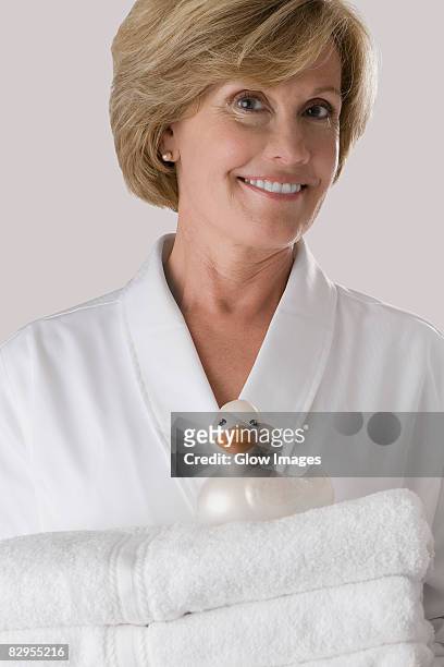 portrait of a mature woman holding a stack of folded towels - alleen één oudere vrouw stockfoto's en -beelden