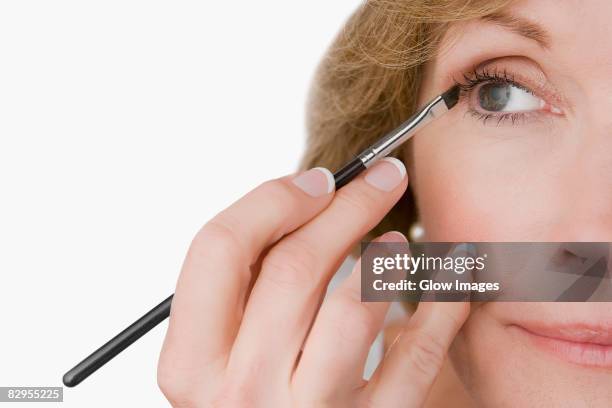 close-up of a mature woman applying eyeliner - eye liner stock pictures, royalty-free photos & images