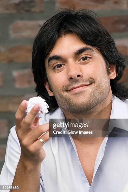 portrait of a young man holding a paper ball and smirking - crumpled paper ball stock-fotos und bilder