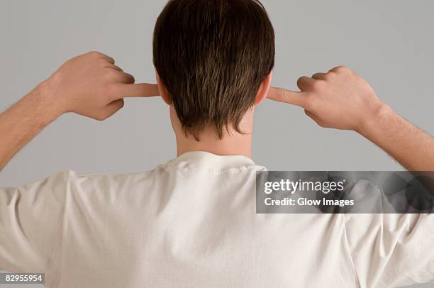 rear view of a young man with his fingers in his ears - fingers in ears 個照片及圖片檔