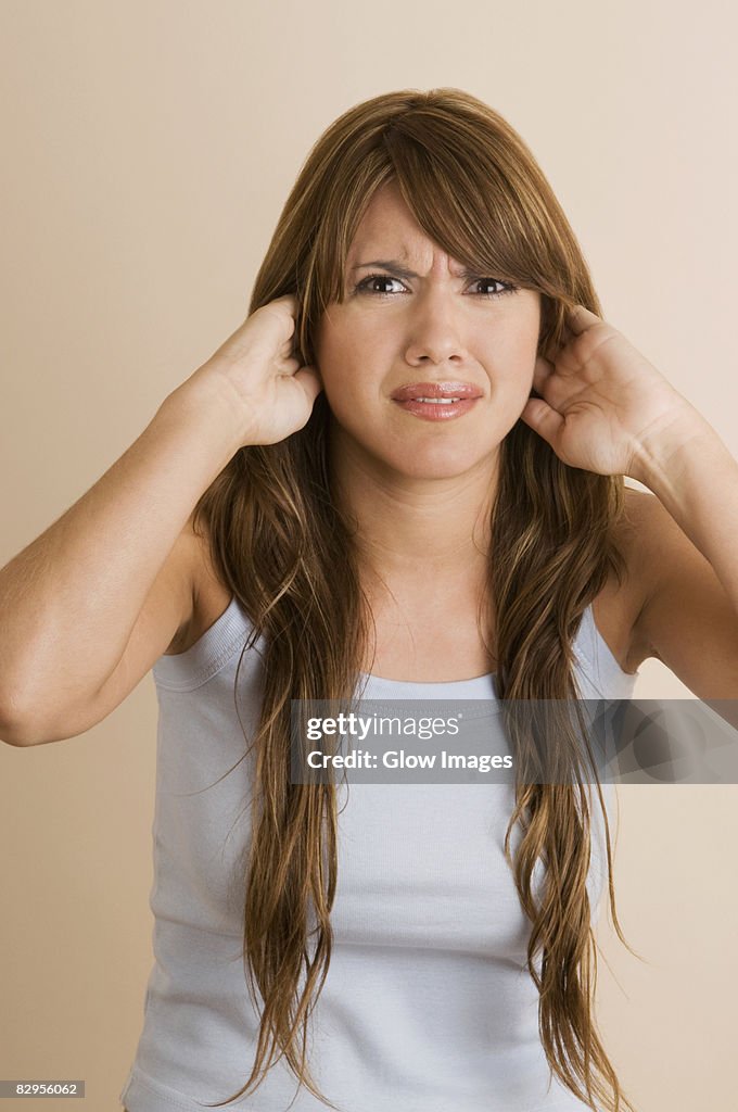 Portrait of a young woman covering her ears with her hands