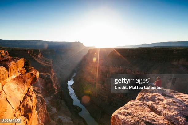 tourist on the edge of the grand canyon at sunrise, usa - versante nord del grand canyon foto e immagini stock