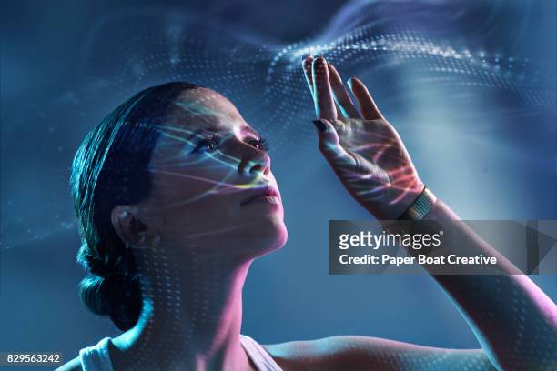 A lady looking up at a computer generated data wave, touching one tip of the wave, shot against a blue background