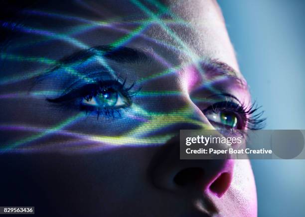 thin light beams going across the eyes of a woman, shot against a blue studio background - grüne augen stock-fotos und bilder