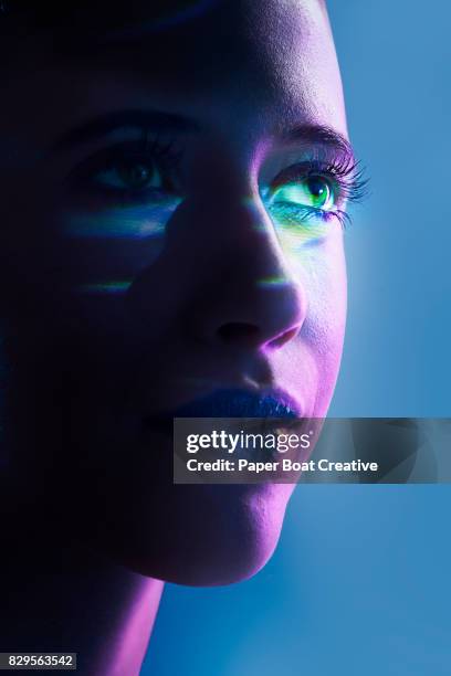 colored prism with laser light reflecting on the face of a woman, shot close up against a blue background - long exposure face stock pictures, royalty-free photos & images