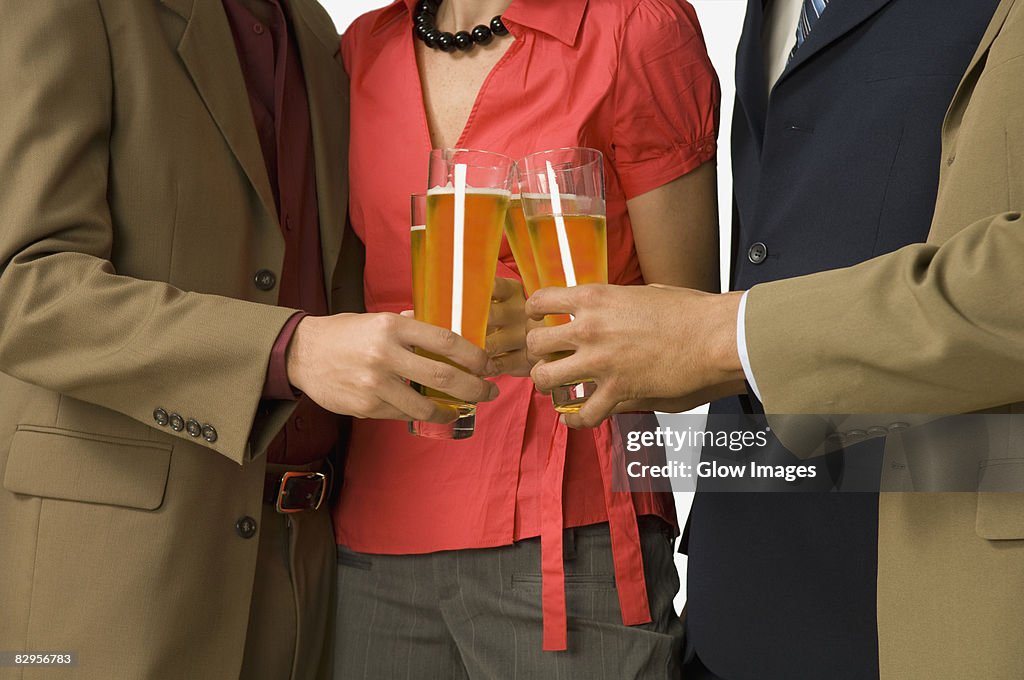 Mid section view of four business executives toasting with glasses of beer