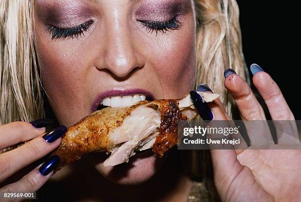 young woman eating chicken leg, close up - hühnchenunterschenkel stock-fotos und bilder