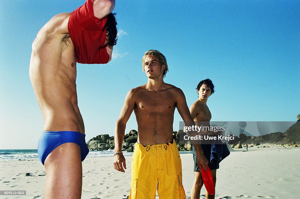 Three young men wearing swimwear on beach