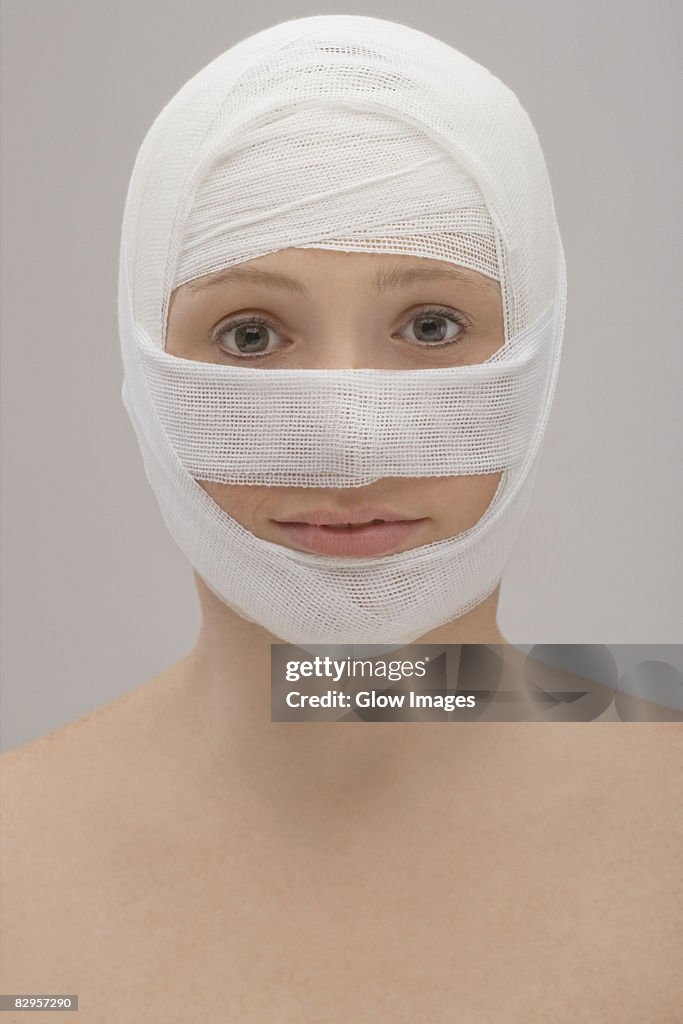 Close-up of a young woman's face wrapped with a bandage