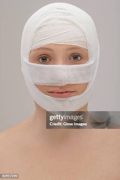 close-up of a young woman's face wrapped with a bandage - head bandage stock-fotos und bilder