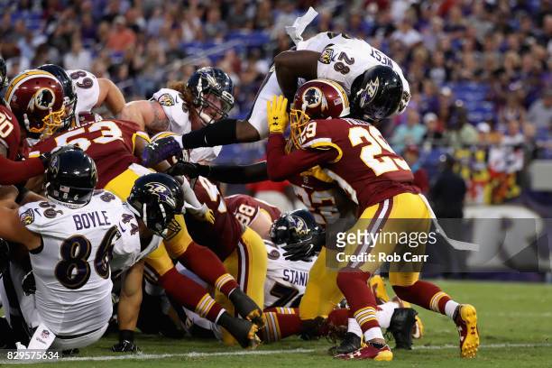 Running back Terrance West of the Baltimore Ravens is hit by cornerback Kendall Fuller of the Washington Redskins while scoring a first quarter...