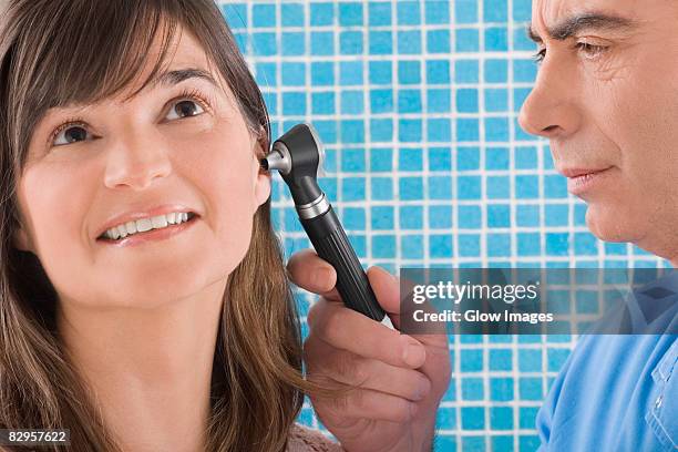 close-up of a male doctor examining a mature woman's ear - ear close up women stock-fotos und bilder