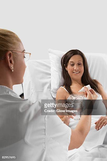 female doctor giving medicine to a mature woman - woman back pillow blonde stock pictures, royalty-free photos & images
