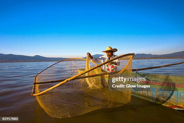 fisherman with butterfly fishing net in a lake, janitzio island, lake patzcuaro, patzcuaro, michoacan state, mexico - état du michoacan photos et images de collection