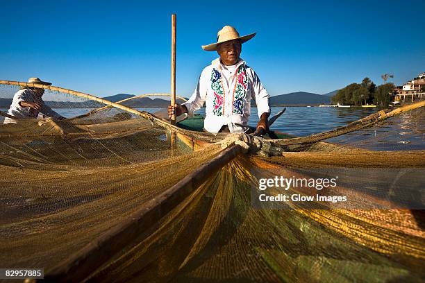 fisherman with butterfly fishing net in a lake, janitzio island, lake patzcuaro, patzcuaro, michoacan state, mexico - état du michoacan photos et images de collection