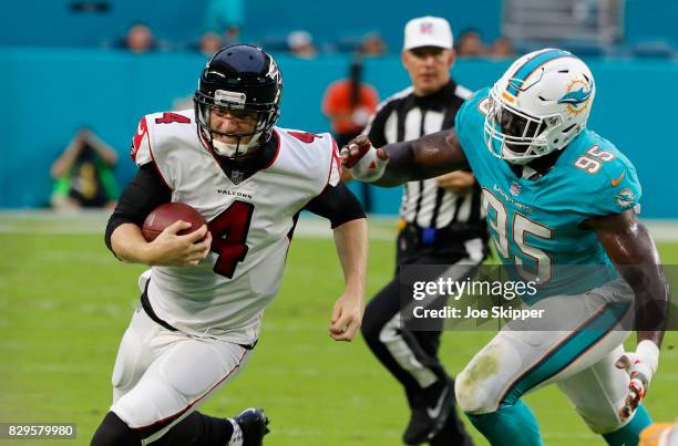 Matt Simms of the Atlanta Falcons scrambles to elude Walt Aikens of the Miami Dolphins during a preseason game at Hard Rock Stadium on August 10,...