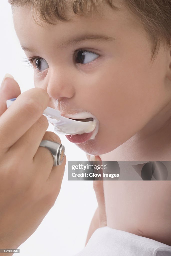 Close-up of a woman's hand feeding her son with a spoon