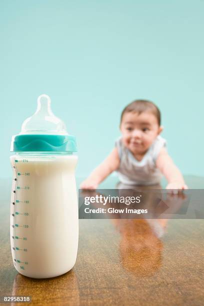 close-up of a milk bottle with a baby boy in the background - milk bottles stock pictures, royalty-free photos & images