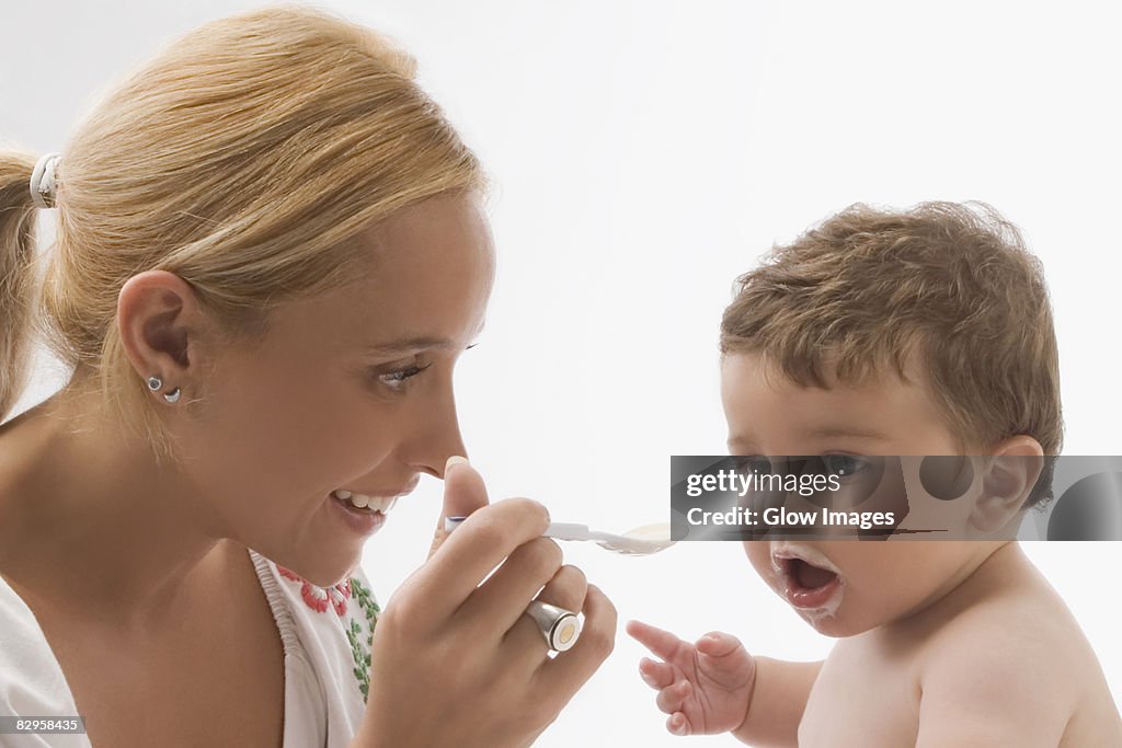 Mid adult woman feeding her son with a spoon and smiling