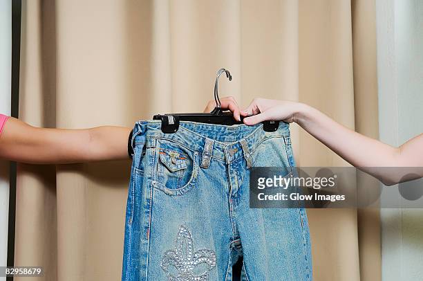 sales clerk giving a jeans to a customer's hand - kleidung anprobe stock-fotos und bilder