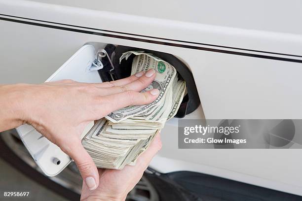 close-up of a person's hands putting us paper currency in a gas tank of a car - gas tank 個照片及圖片檔