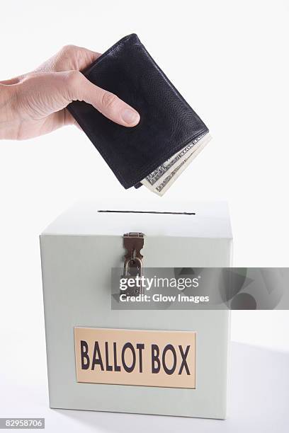 close-up of a person's hand putting money full of wallet into a ballot box - ballot box money stock pictures, royalty-free photos & images