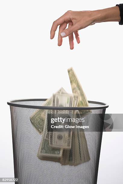 close-up of a person's hand throwing us dollar bills in a garbage bin - waste wealth stock pictures, royalty-free photos & images