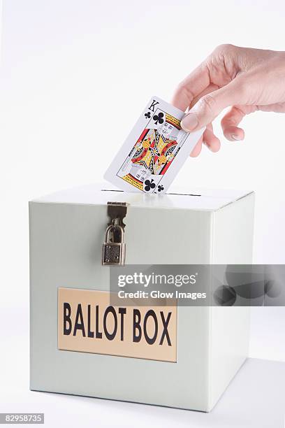 person's hand inserting a playing card into a ballot box - rey de trébol fotografías e imágenes de stock