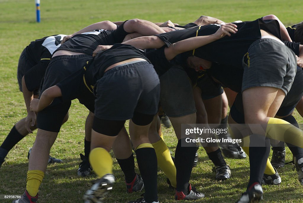 Rugby players forming scrum in a field