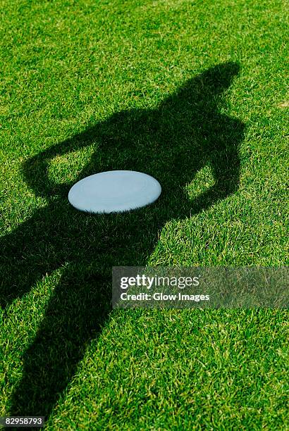 high angle view of a shadow of a person with a plastic disc in a park - flying disc stock pictures, royalty-free photos & images