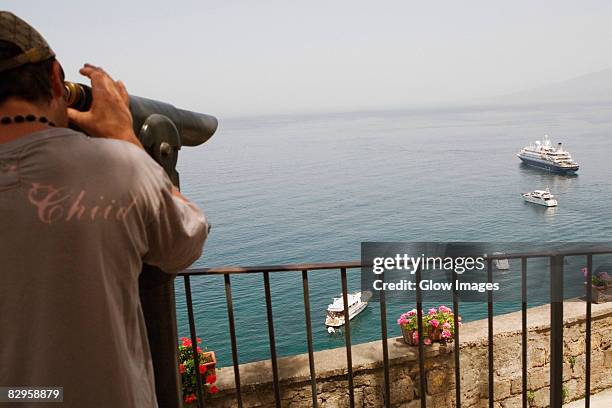 rear view of a man looking through a coin-operated binocular, bay of naples, via aniello califano, sorrento, sorrentine peninsula, naples province, campania, italy - anello stock pictures, royalty-free photos & images