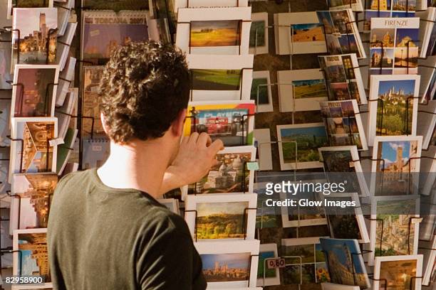 rear view of a man choosing postcards, piazza della cisterna, san gimignano, siena province, tuscany, italy - alternative view portraits stock-fotos und bilder