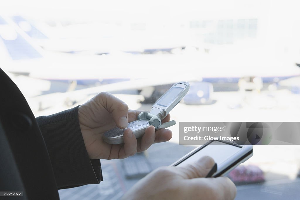 Close-up of a businessman's hands using a mobile phone and a personal data assistant
