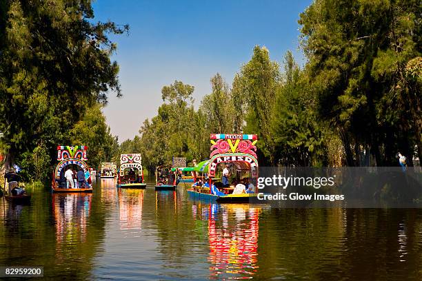 tourists on trajineras boats in a canal, xochimilco gardens, mexico city, mexico - mexico city landmark stock pictures, royalty-free photos & images