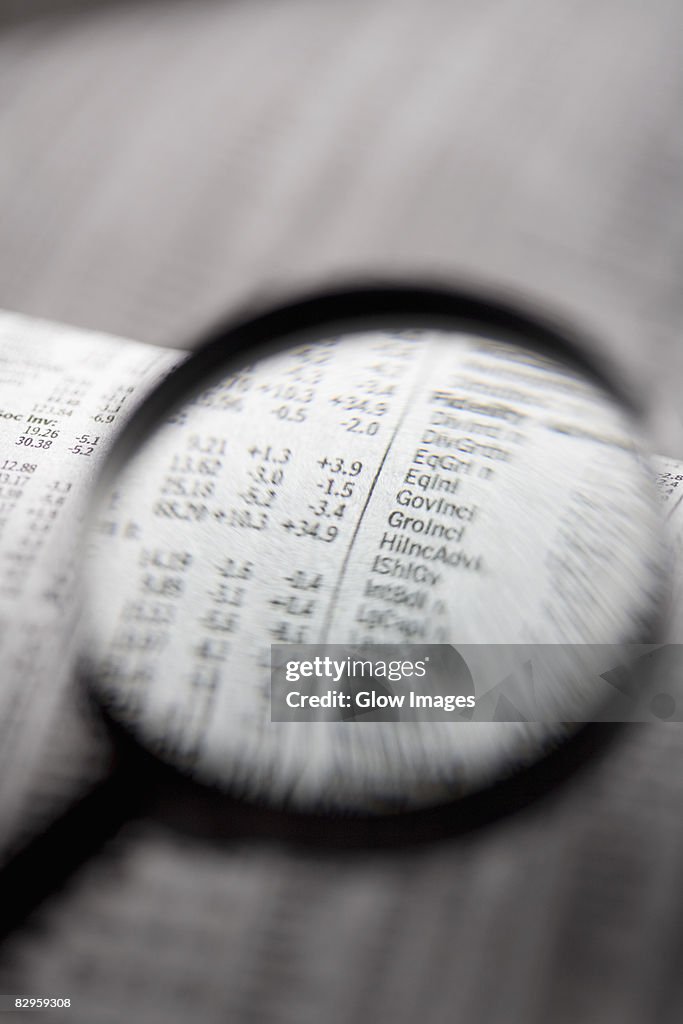 Close-up of a financial newspaper and a magnifying glass