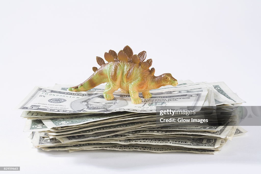 Close-up of a figurine of a dinosaur on a stack of US paper currency