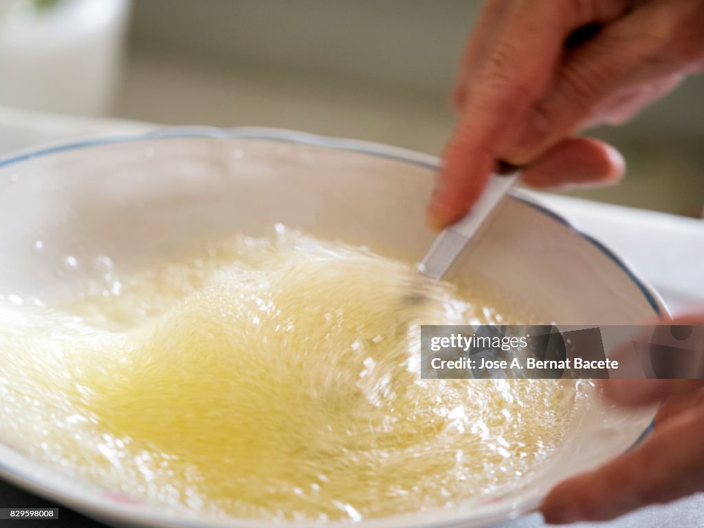 Hands of a woman beating eggs on a plate for the preparation of a Spanish omelette, Spain