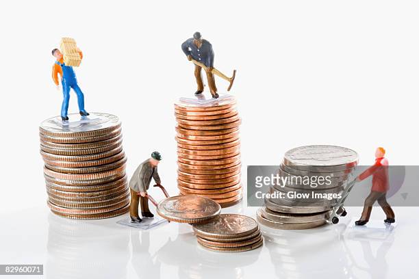 figurines of manual workers with stacks of coins - miniature foto e immagini stock
