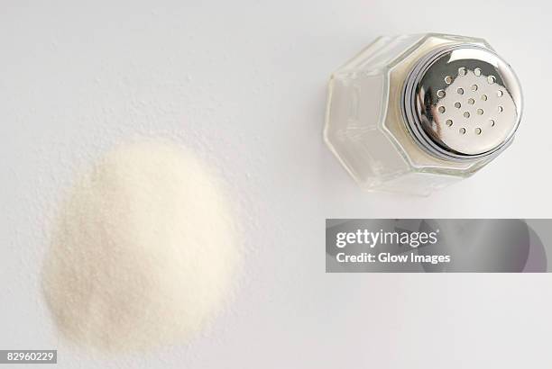 high angle view of a salt shaker with a heap of salt - salt shaker stockfoto's en -beelden