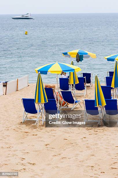 lounge chairs and beach umbrellas on the beach, plage de la croisette, cote d'azur, cannes, provence-alpes-cote d'azur, france - parasol de plage fotografías e imágenes de stock