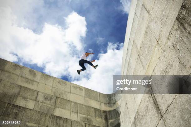 young man stride jumping on concrete wall - flexibility stock pictures, royalty-free photos & images