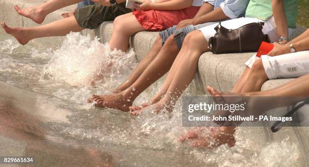 Group of visitors to the Princess Diana Memorial fountain in Hyde Park, London, take the opportunity to cool off their feet in the water, as...