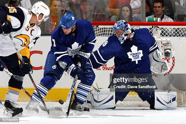 Goaltender Justin Pogge of the Toronto Maple Leafs makes a save as teammate Ian White and Jochen Hecht of the Buffalo Sabres battle for the puck...